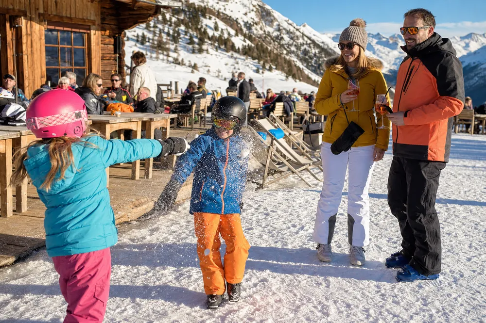 Children in ski helmets playing in the snow outside a mountain restaurant