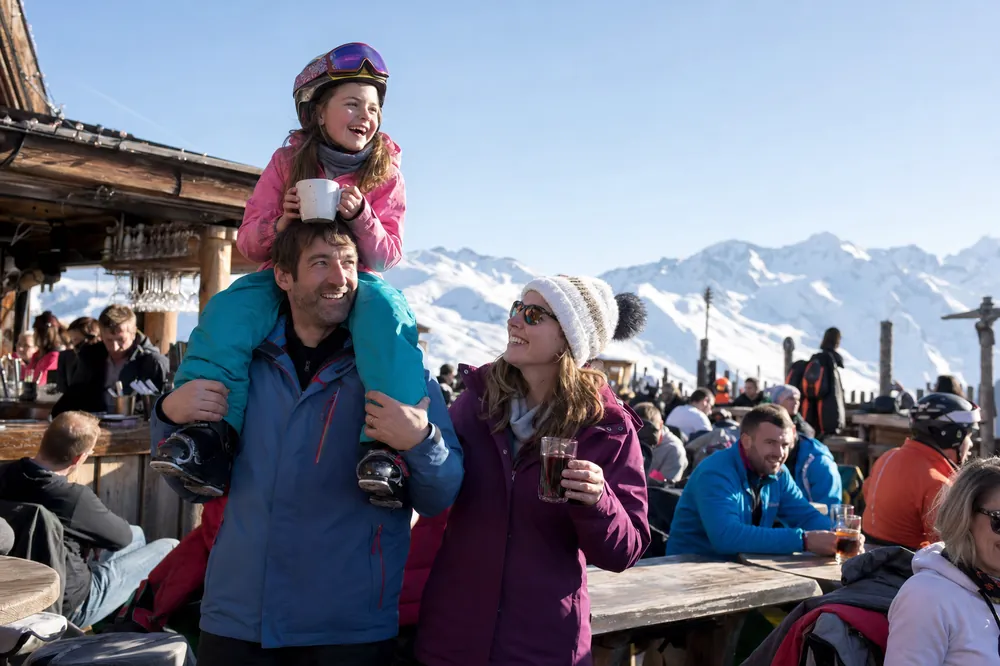 Dad carrying his daughter on his shoulders on a sunny terrace in the Alps